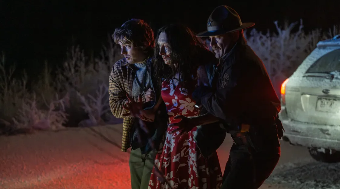 Austin Abrams junto a otros dos personajes en una calle nevada de noche en Resident Evil: Noche Cero