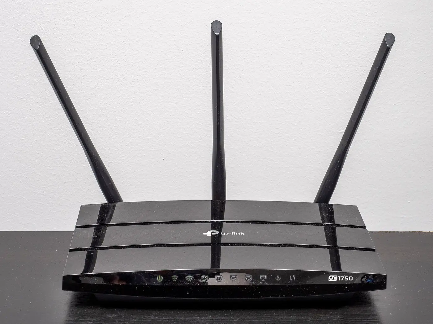 Router wifi hogareño negro con tres antenas apoyado sobre un mueble