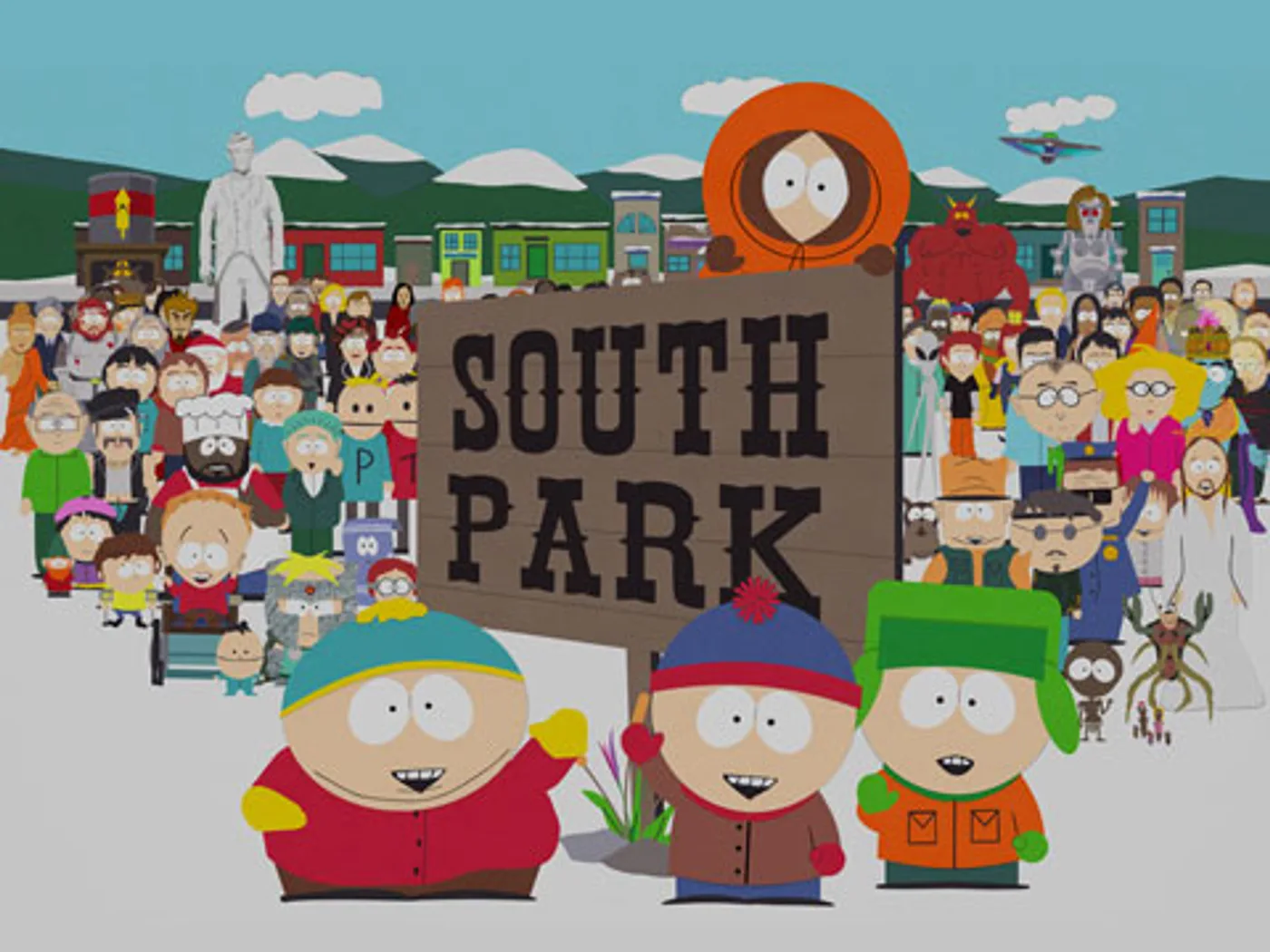 Cartman, Stan y Kyle frente al cartel original de South Park, con Kenny sentado arriba y los vecinos del pueblo detrás