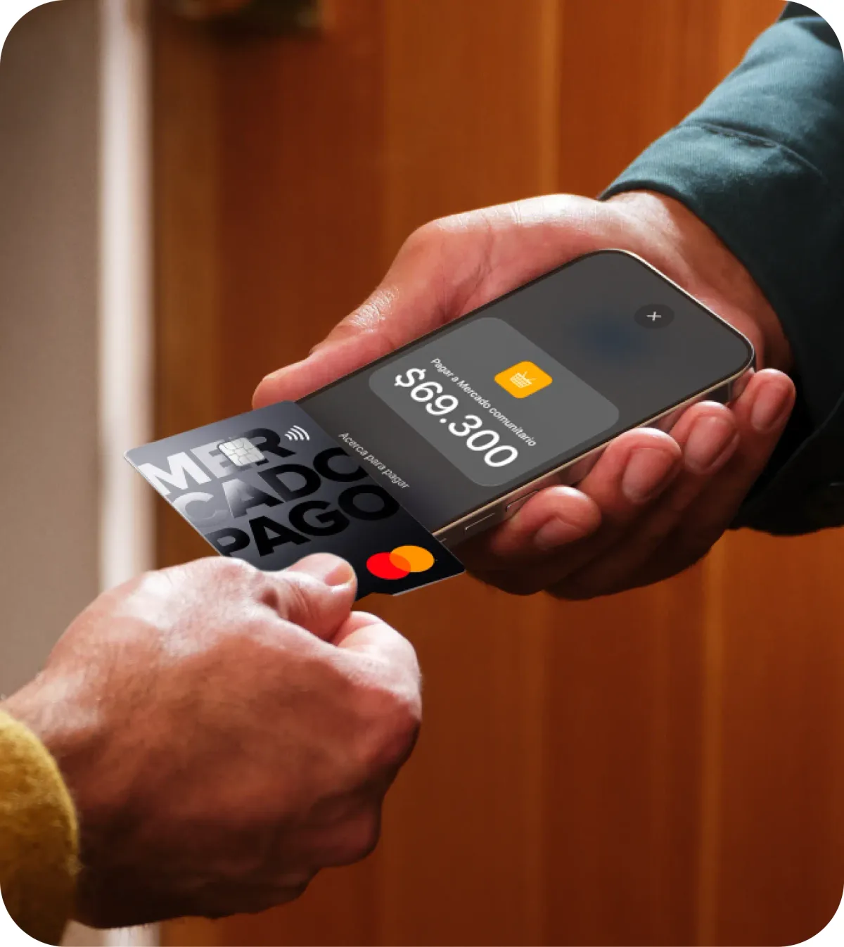 Un comerciante sostiene un iPhone y cobra con Tap to Pay mientras el cliente apoya una tarjeta de Mercado Pago sobre la pantalla