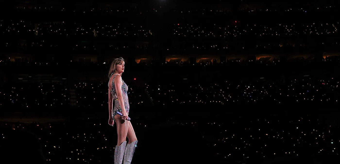 Taylor Swift sola en el escenario durante el set de Lover del Eras Tour, con el estadio a oscuras y las luces de los celulares del público