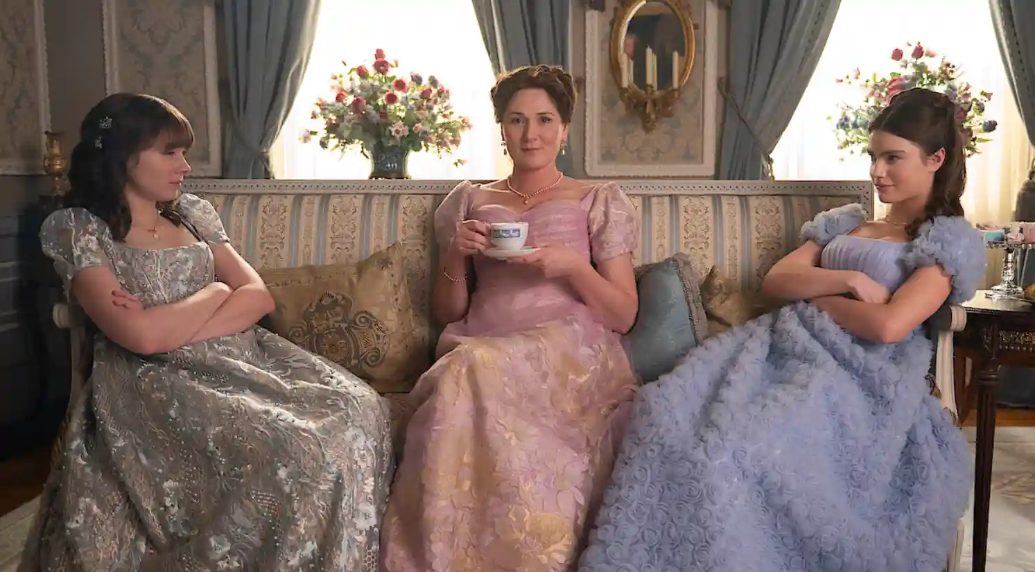 Eloise, Violet y Hyacinth Bridgerton sentadas en un sillón en una escena de la serie de Netflix