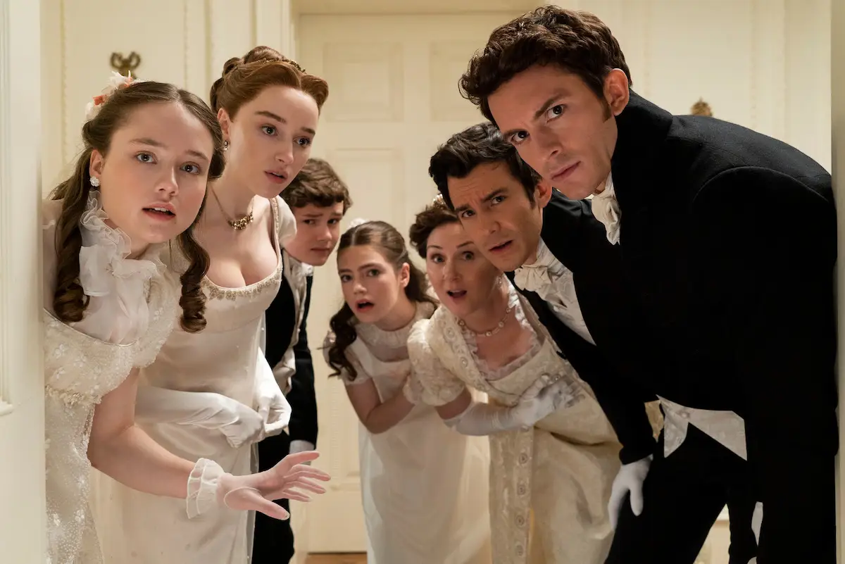 Los hermanos Bridgerton espiando detrás de una puerta en una escena de la serie de Netflix