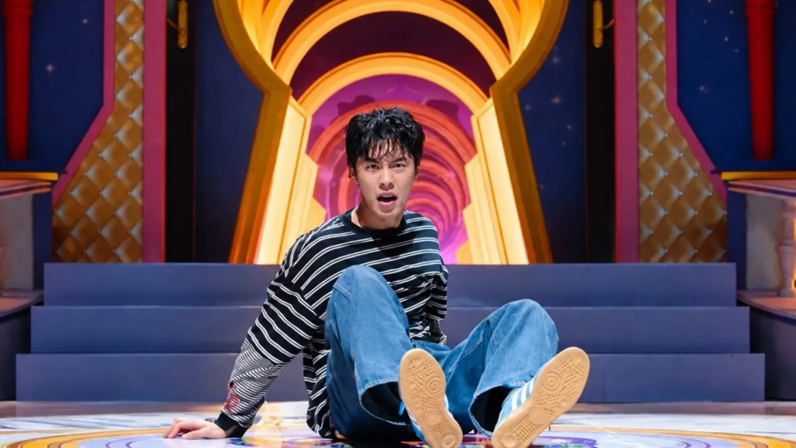Lee Jae-wook sentado en el piso de un pasillo de colores en Un trabajo maldito, la serie coreana de terror de Netflix