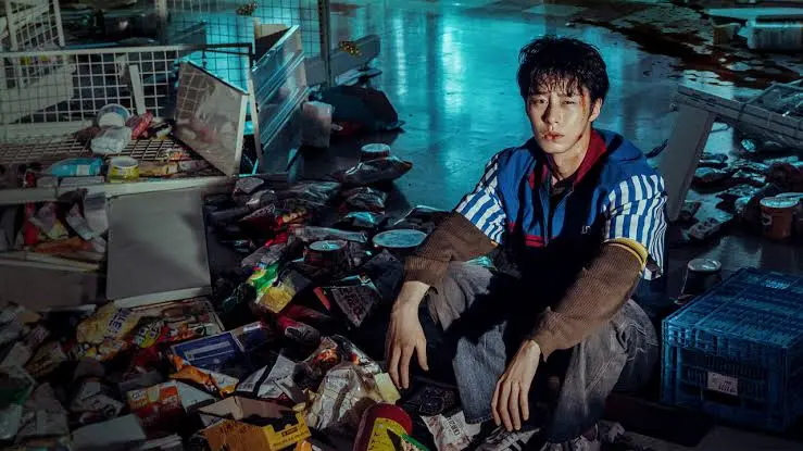 Lee Jae-wook lastimado y rodeado de productos de supermercado tirados en Un trabajo maldito, de Netflix