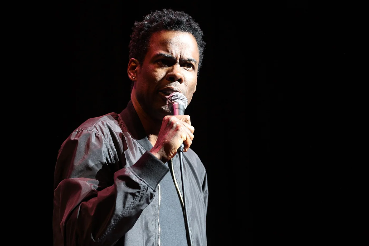 Chris Rock con un micrófono en la mano durante un show de stand-up