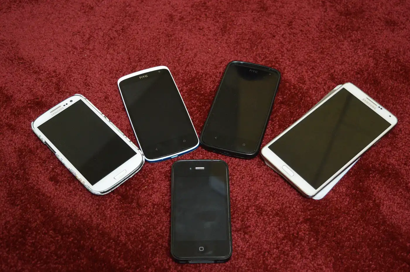 Cinco smartphones de distintas marcas apoyados sobre una alfombra roja