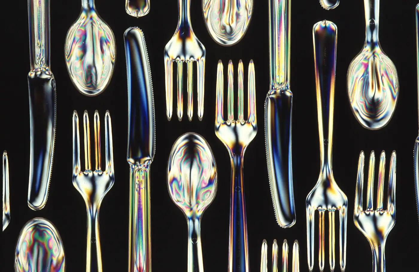 Tenedores, cuchillos y cucharas de plástico descartables sobre fondo negro