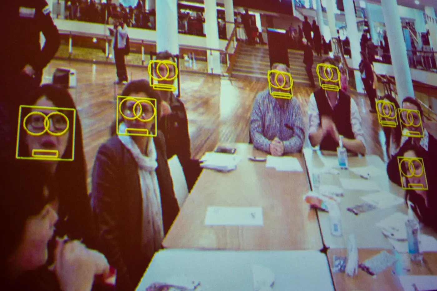 Demostración de un software de reconocimiento facial que marca con recuadros las caras de las personas sentadas en un salón
