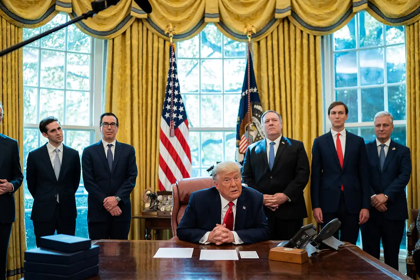 Donald Trump sentado en el escritorio del Salón Oval, rodeado de funcionarios, en octubre de 2020