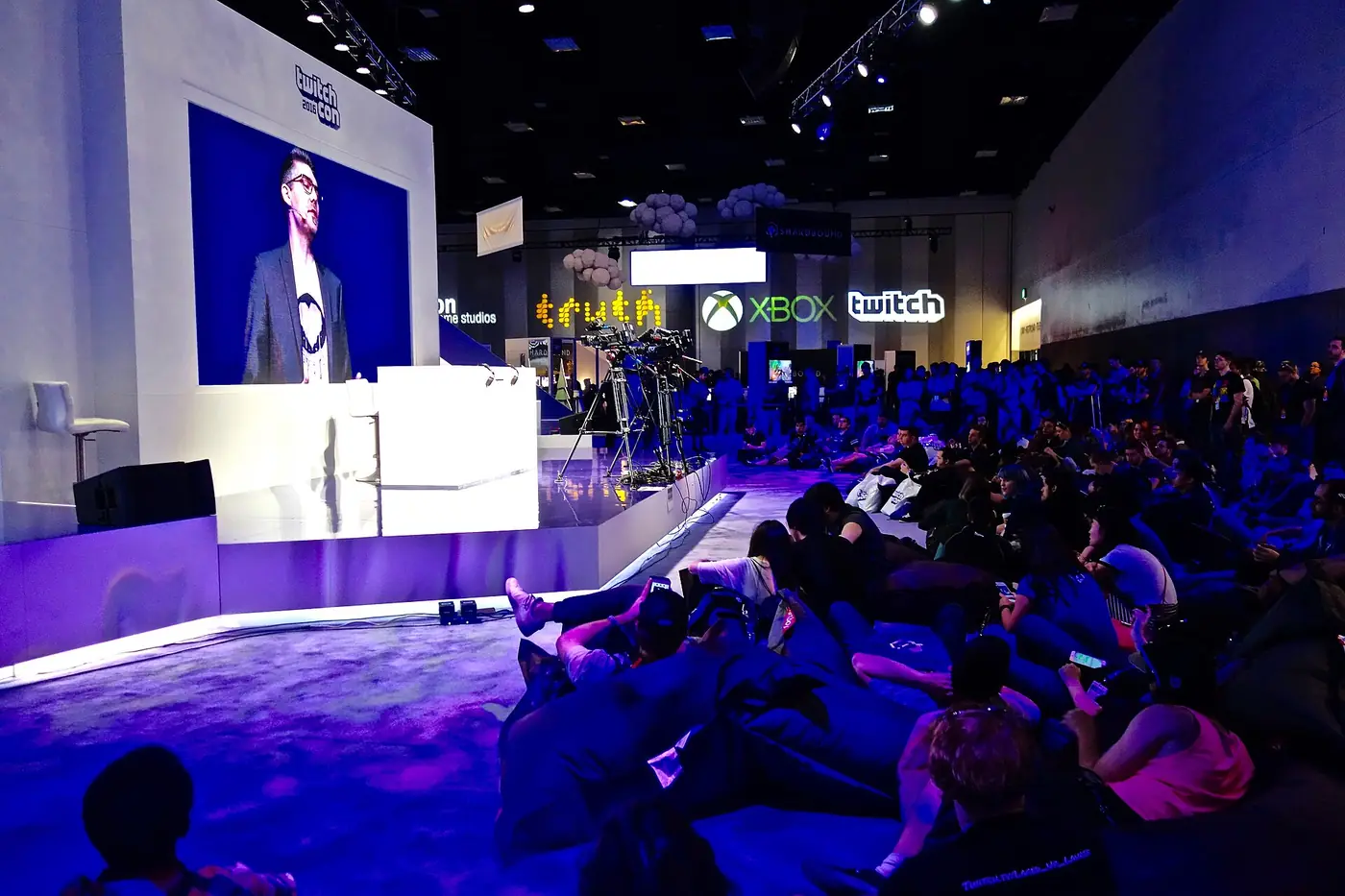 Público frente al escenario principal de la TwitchCon 2016, con una pantalla gigante e iluminación violeta