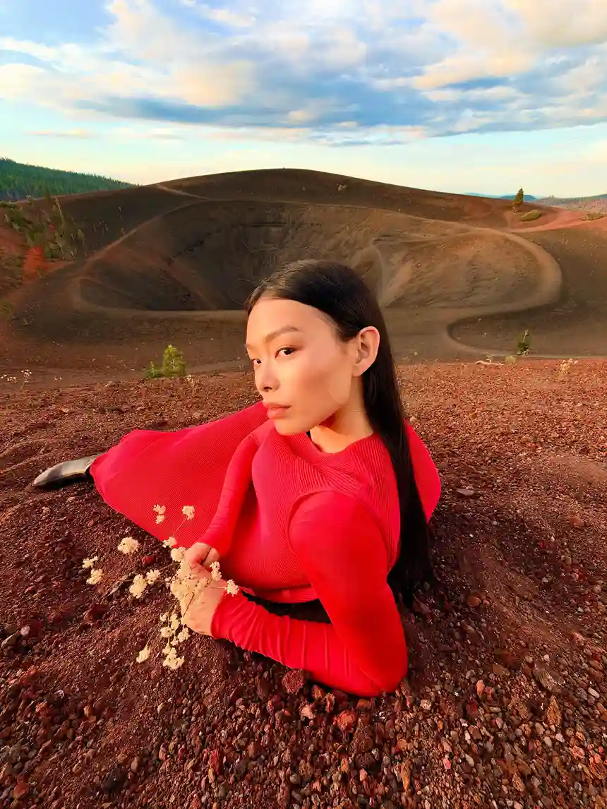 Foto de muestra del iPhone Duo: una mujer vestida de rojo recostada sobre tierra volcánica