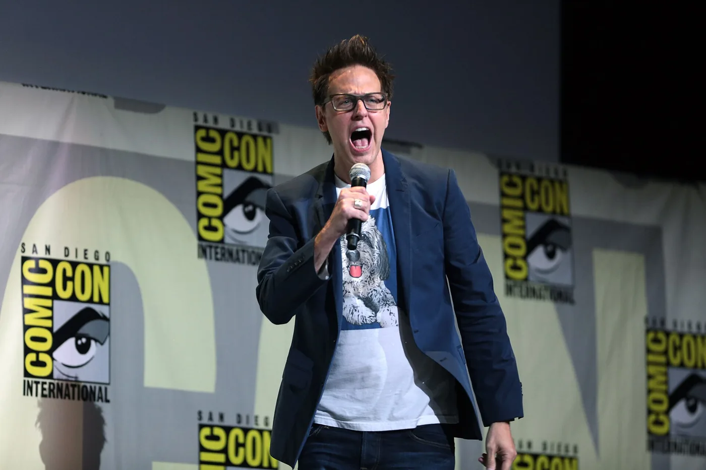 James Gunn grita con un micrófono en la mano durante un panel de la Comic-Con de San Diego