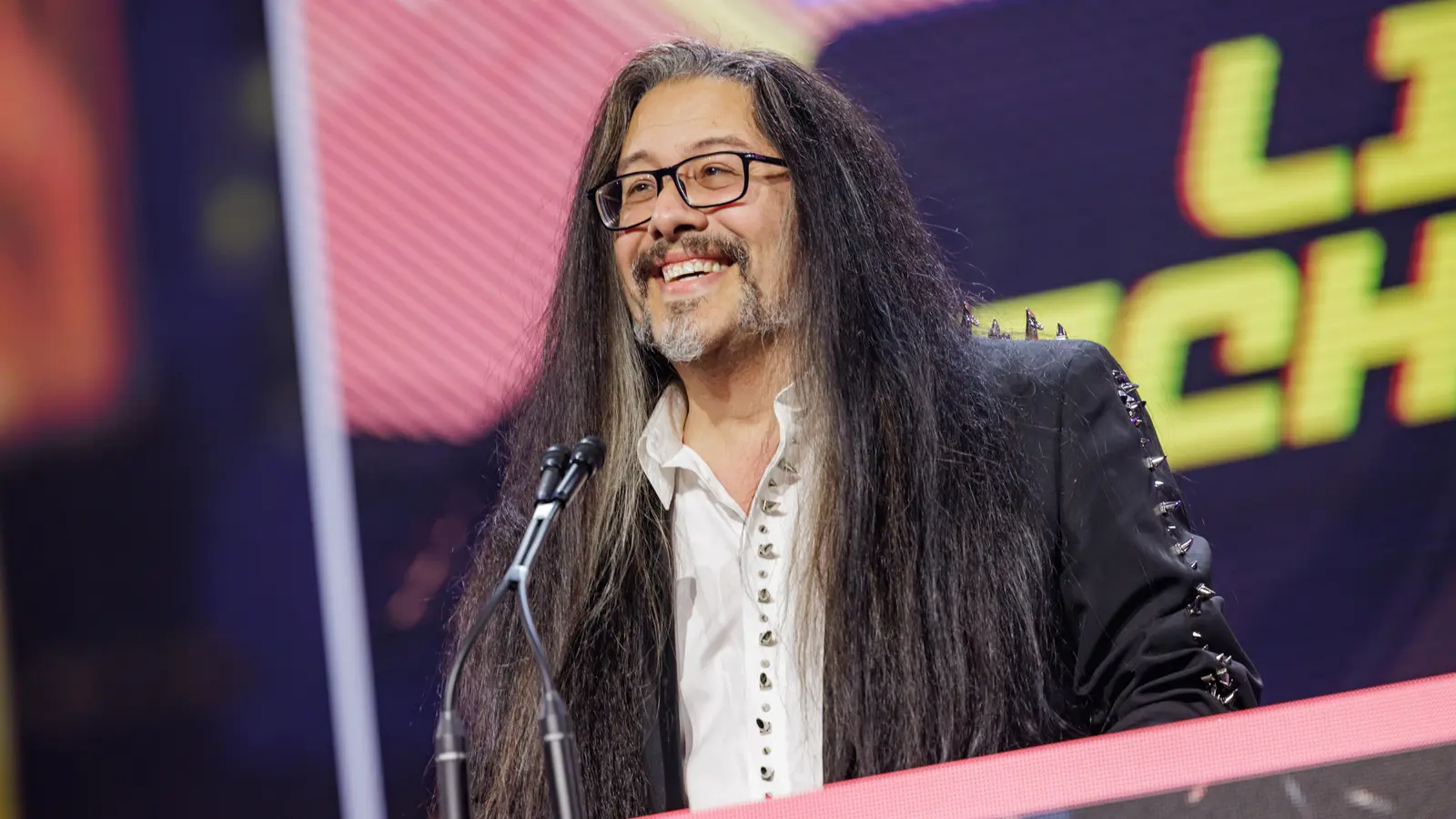 John Romero sonríe en el escenario de la GDC 2023 al recibir el premio a la trayectoria