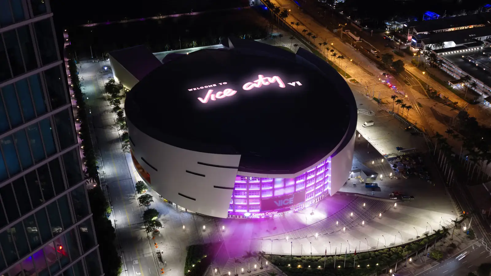 Vista aérea nocturna del Kaseya Center, la cancha del Miami Heat, con el cartel luminoso Welcome to Vice City de GTA 6 en el techo