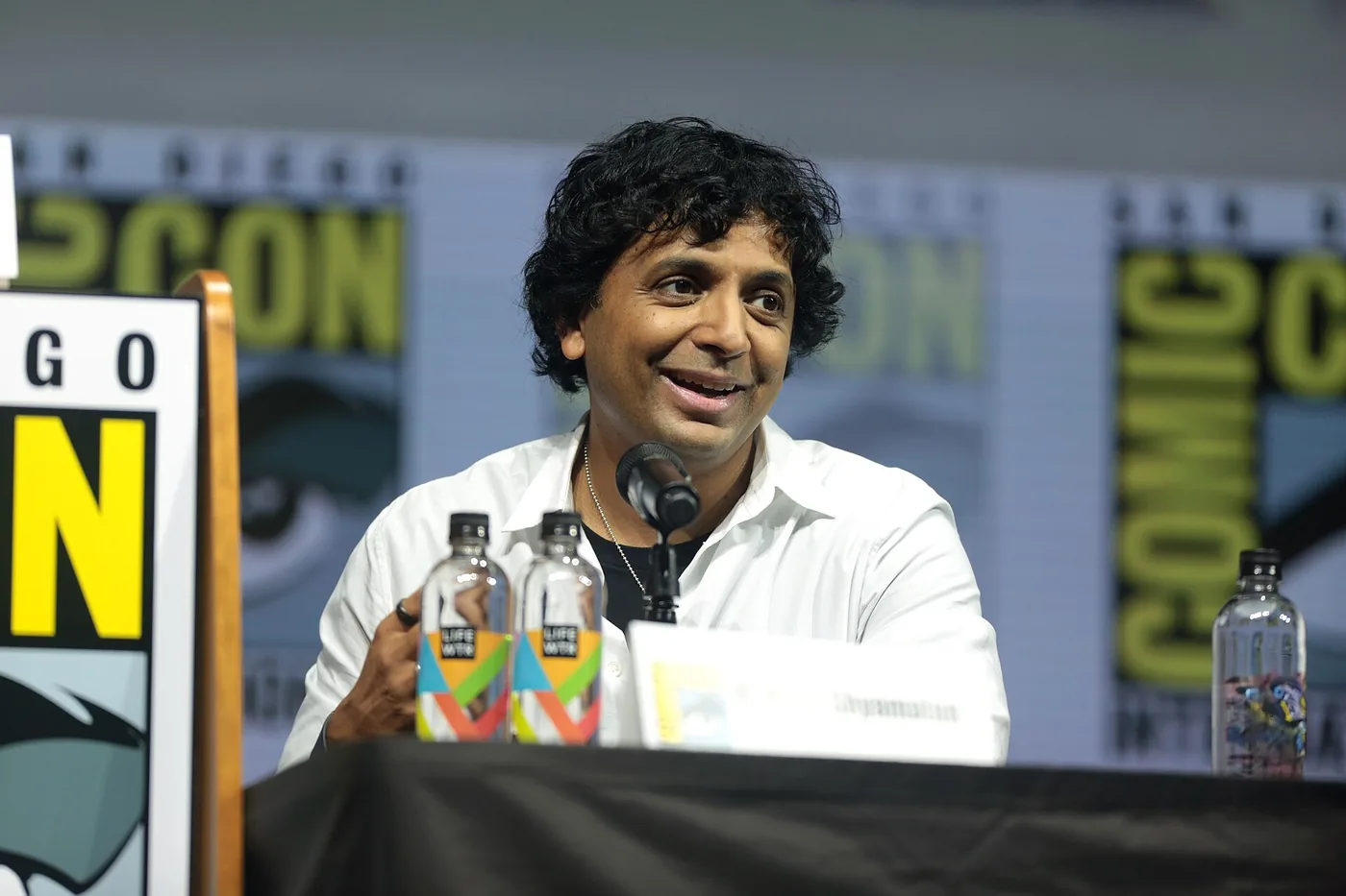 M. Night Shyamalan sonríe sentado en un panel de la Comic-Con de San Diego