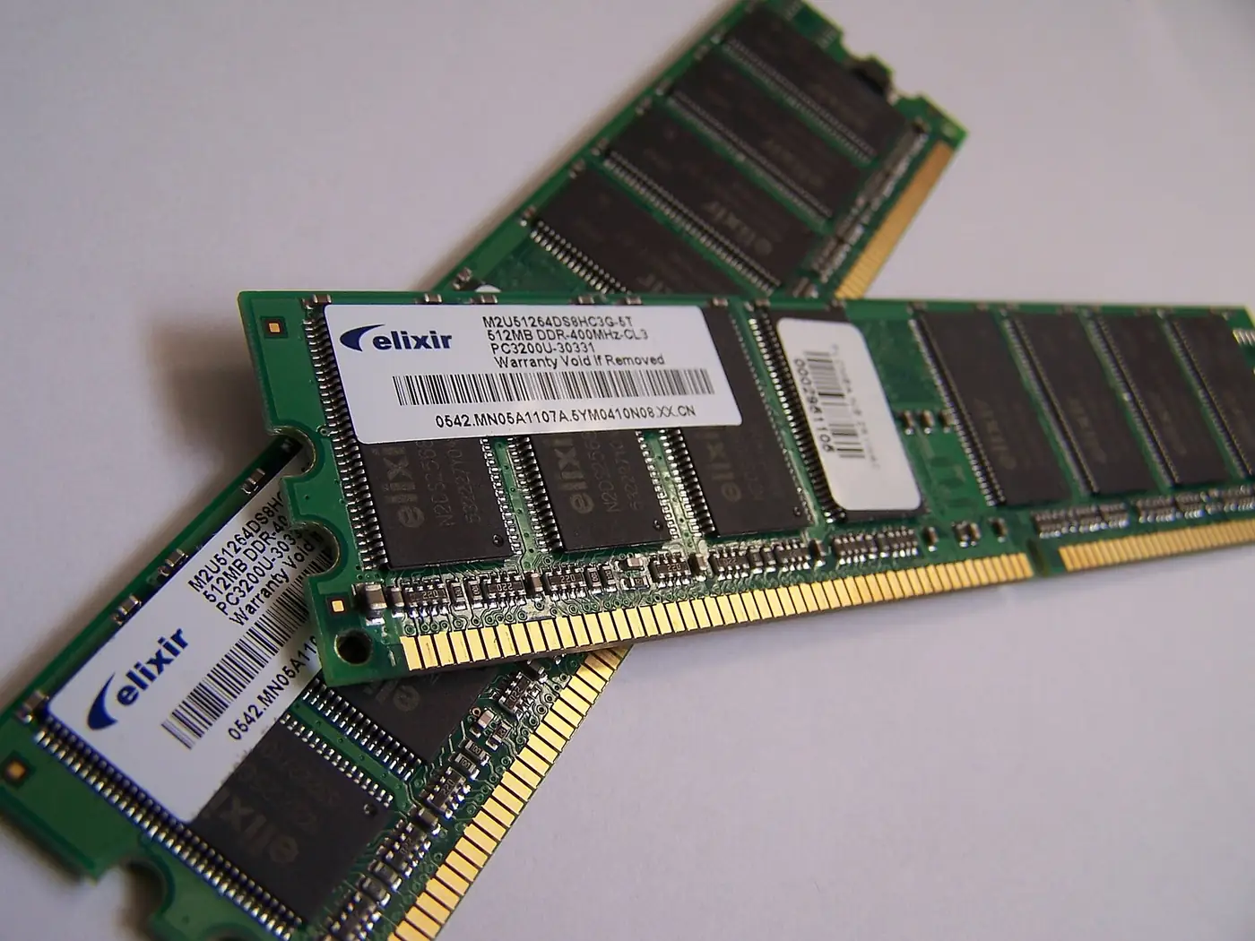 Dos módulos de memoria RAM DDR apoyados sobre una superficie blanca