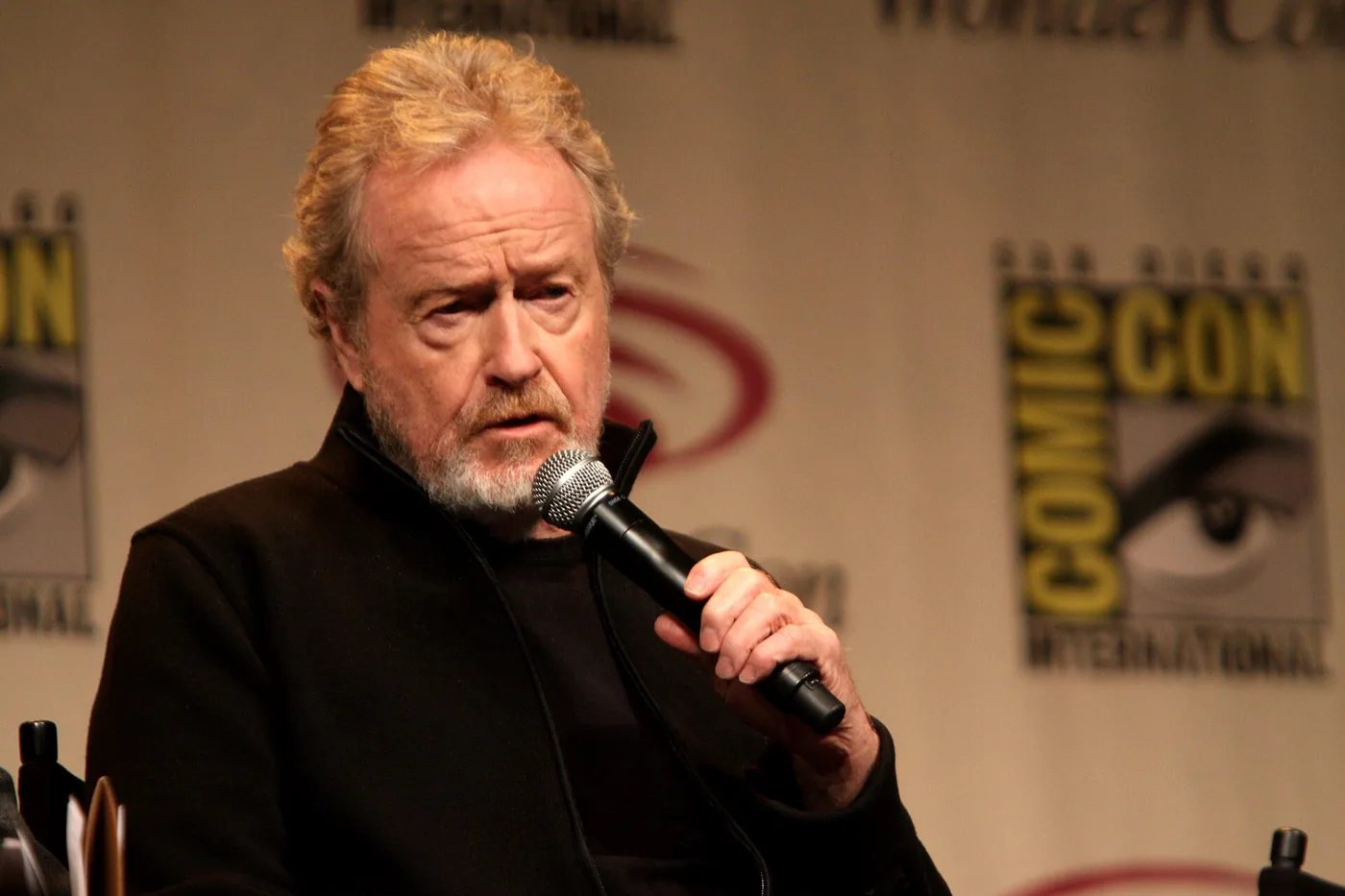 El director Ridley Scott habla con un micrófono durante un panel de WonderCon