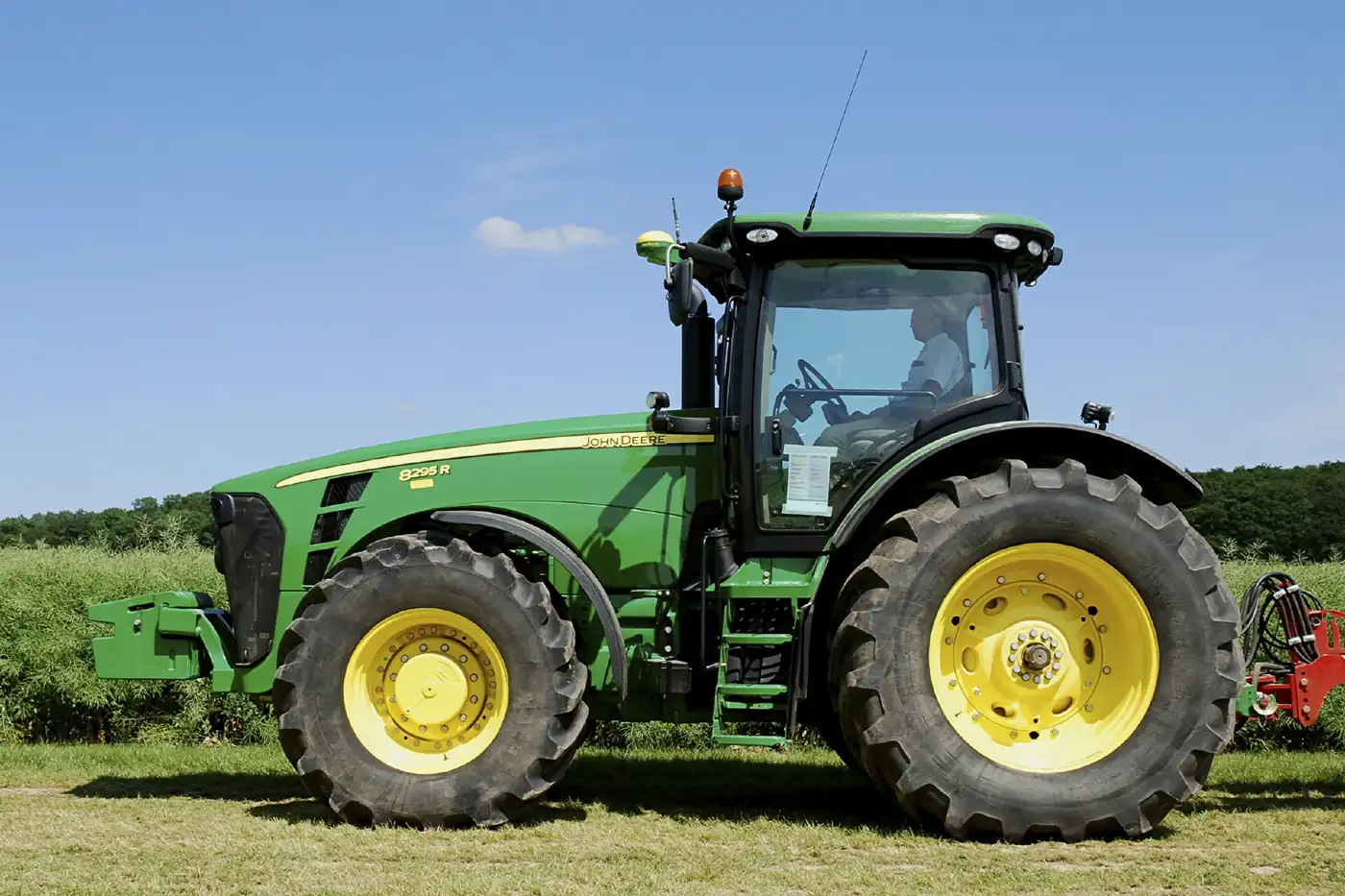Tractor John Deere 8295R verde con el receptor GPS StarFire sobre la cabina, estacionado en un campo