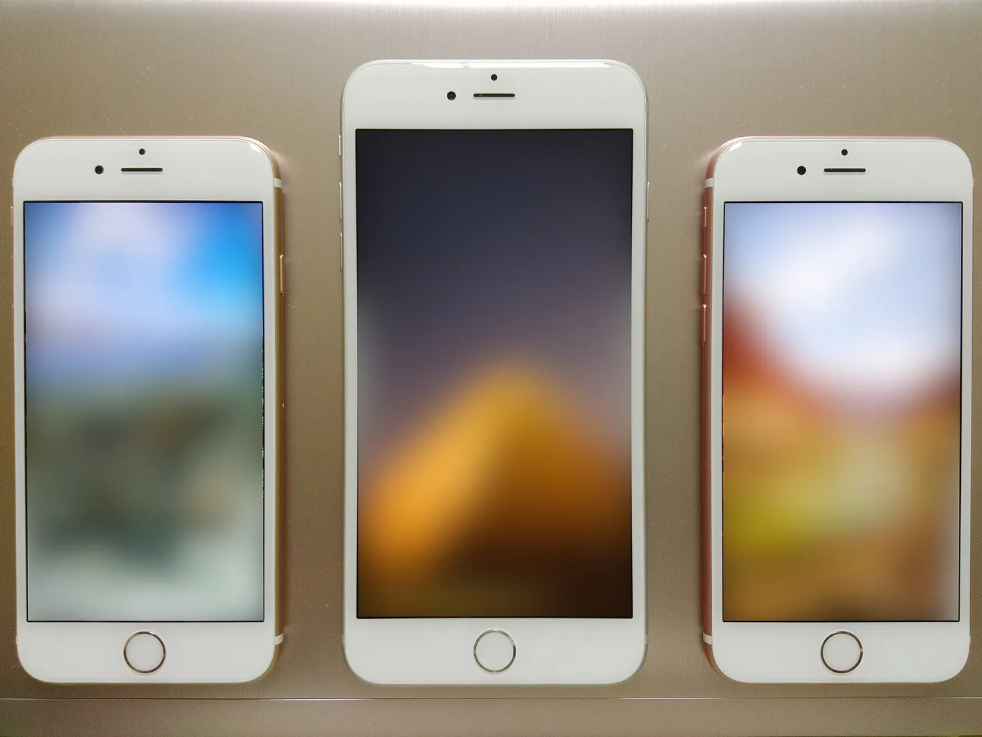 Tres iPhone de generaciones anteriores, de la línea iPhone 6, parados de frente con la pantalla encendida