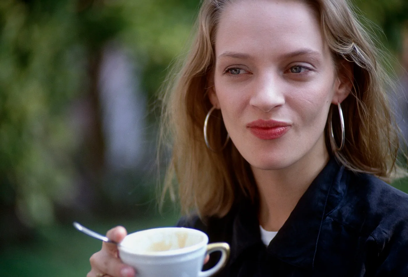 Uma Thurman en 1994, con aros grandes y una taza de café en la mano